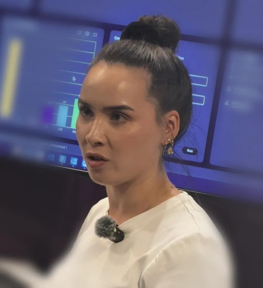 Eline voor een groot scherm met een dashboard, micro op, terwijl ze iets uitlegt.