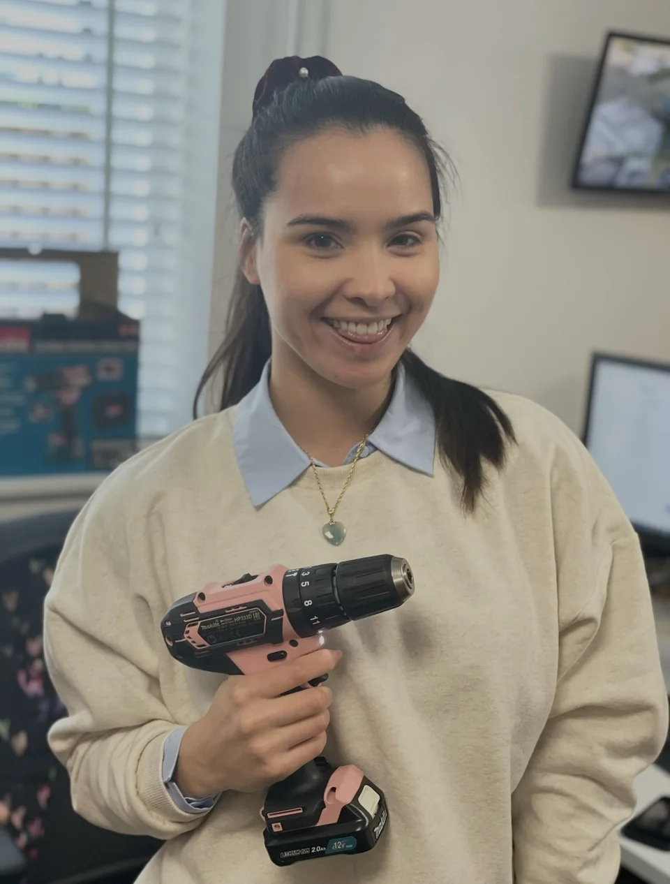 Eline lachend op kantoor met een roze boormachine.