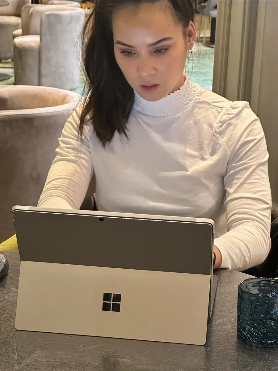 Eline geconcentreerd achter haar laptop, kijkt omlaag naar het scherm.